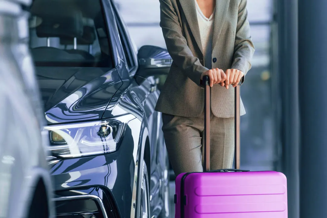 Girl with a purple suitcase near a car