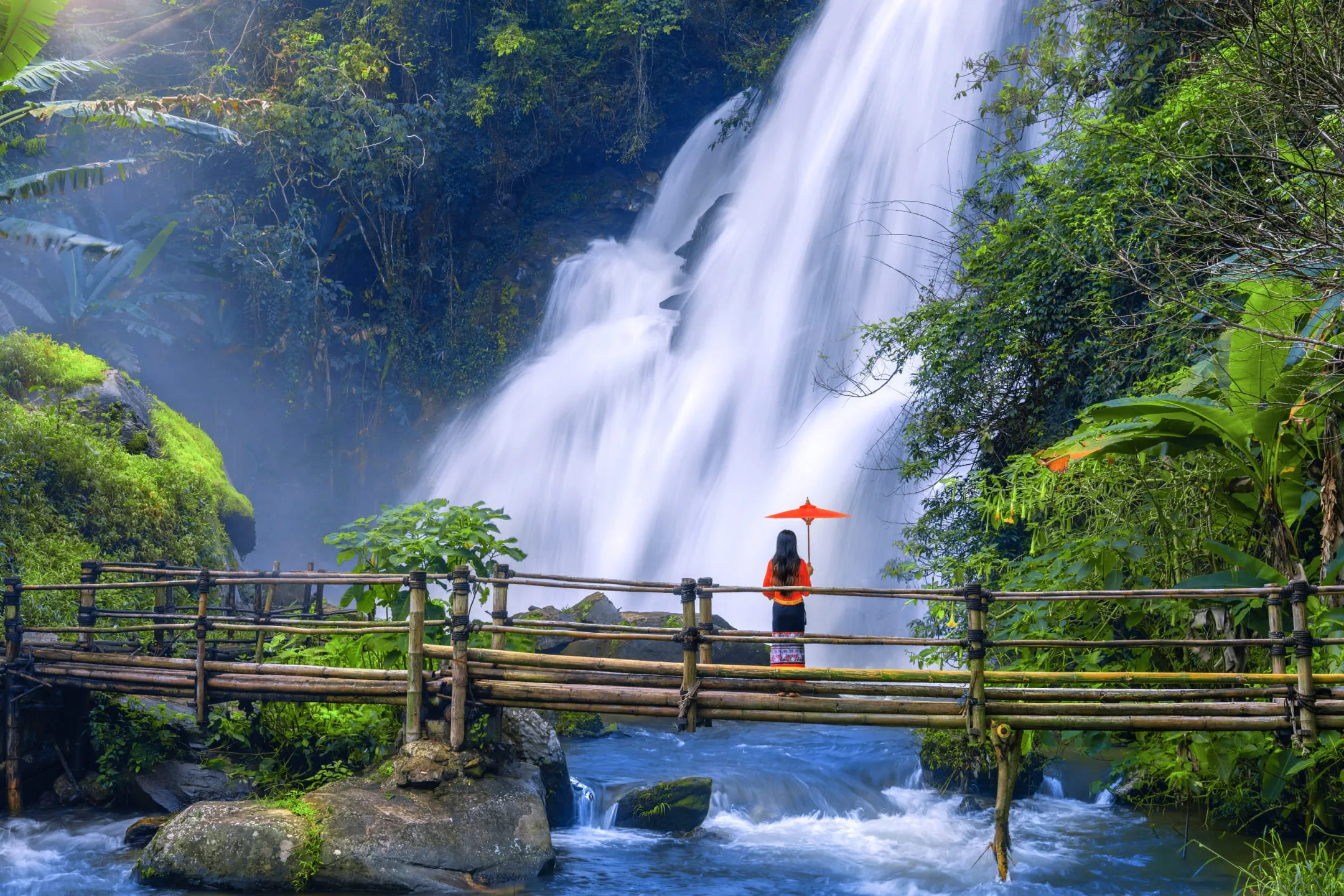 Girl with an umbrella in front of a waterfall
