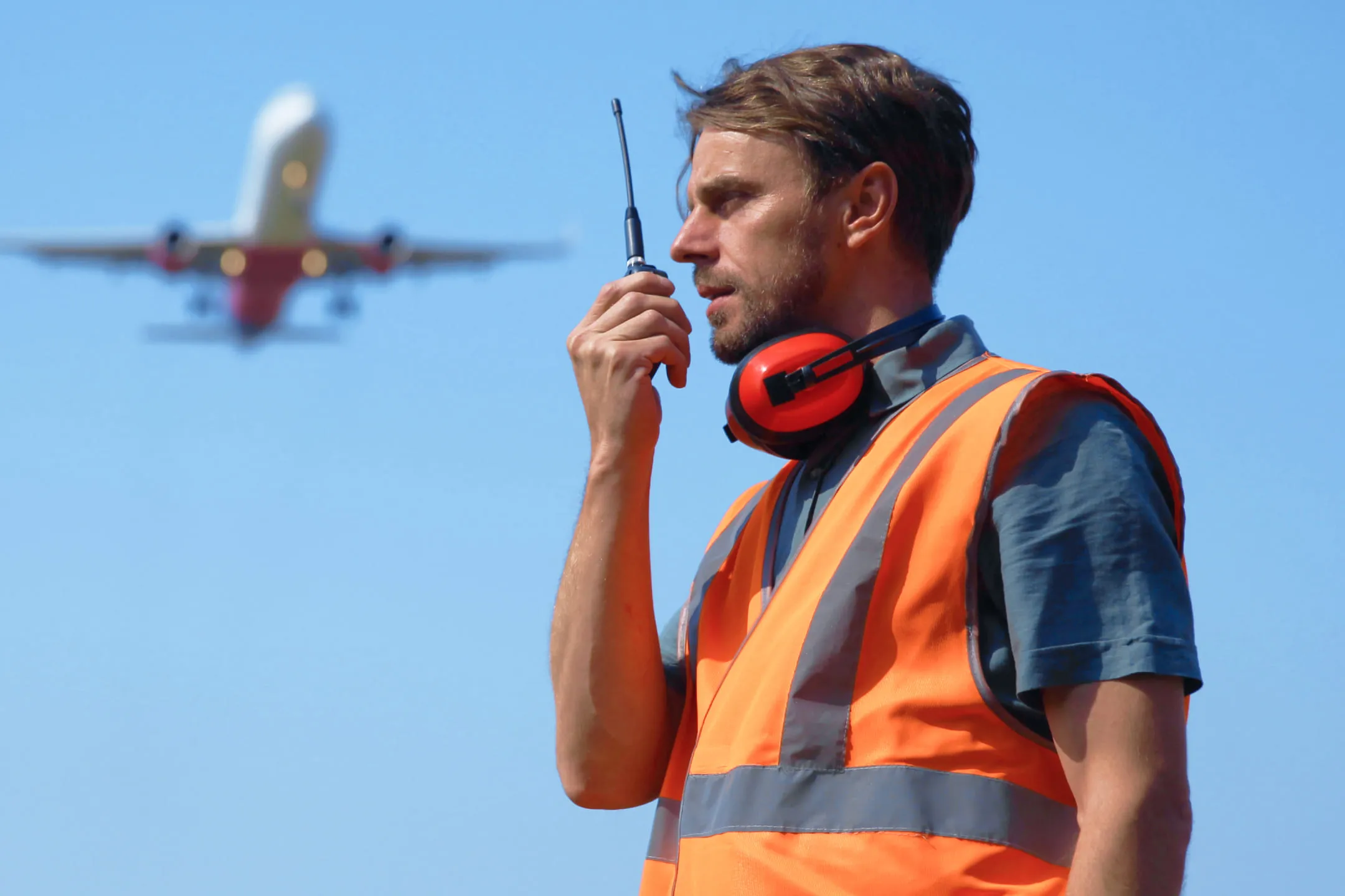 Person in an orange vest talking on a radio