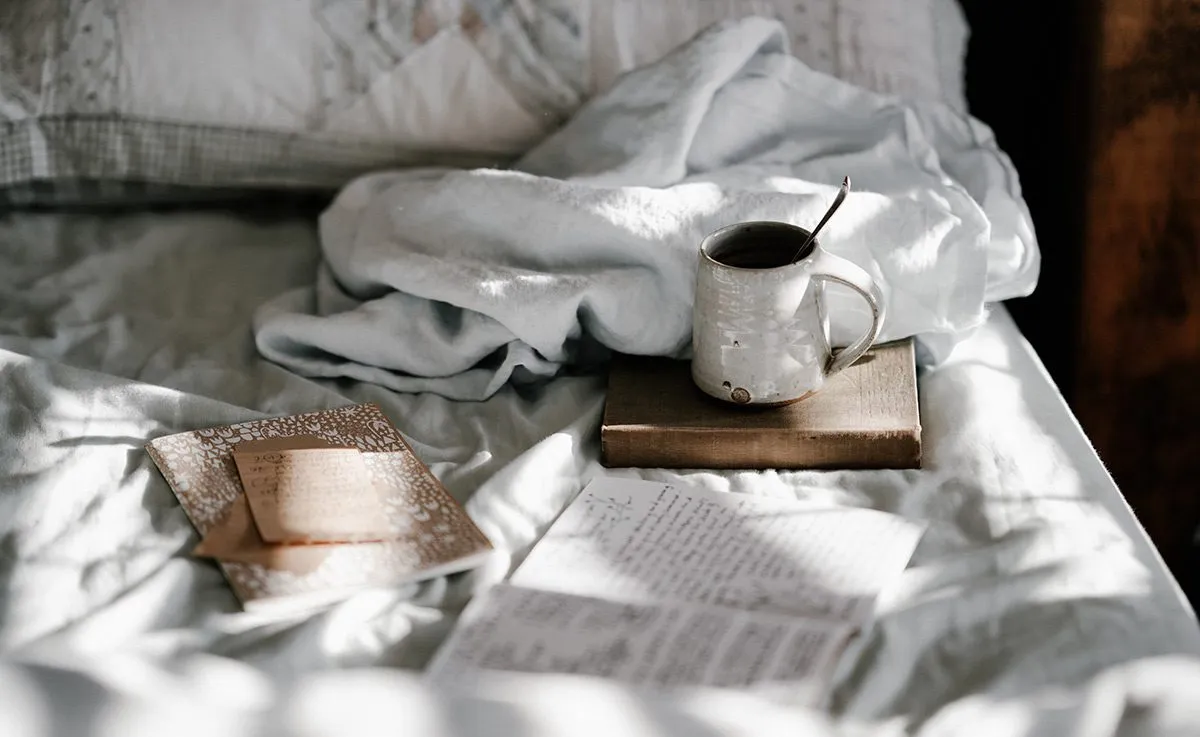 Coffee mug and book on the bed