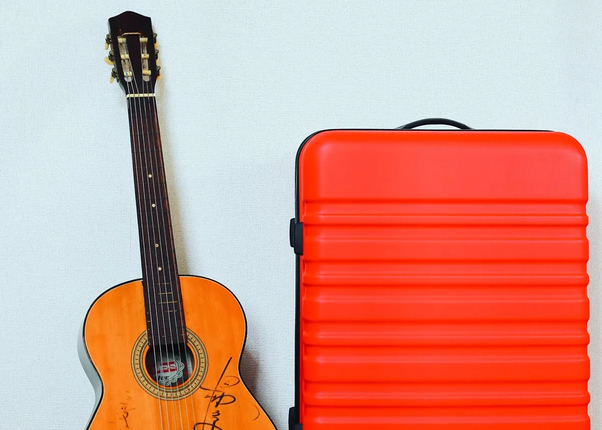 Guitar next to a suitcase