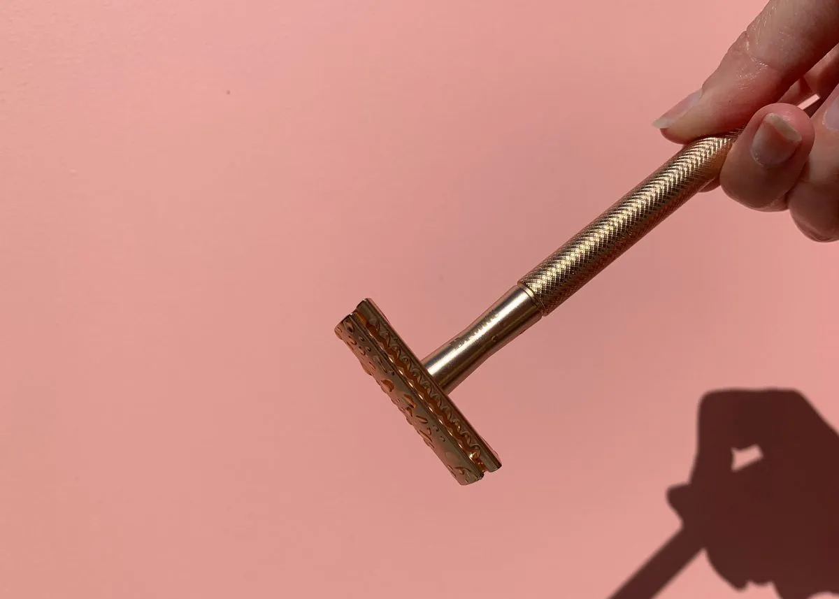 Razor in hands on a pink background