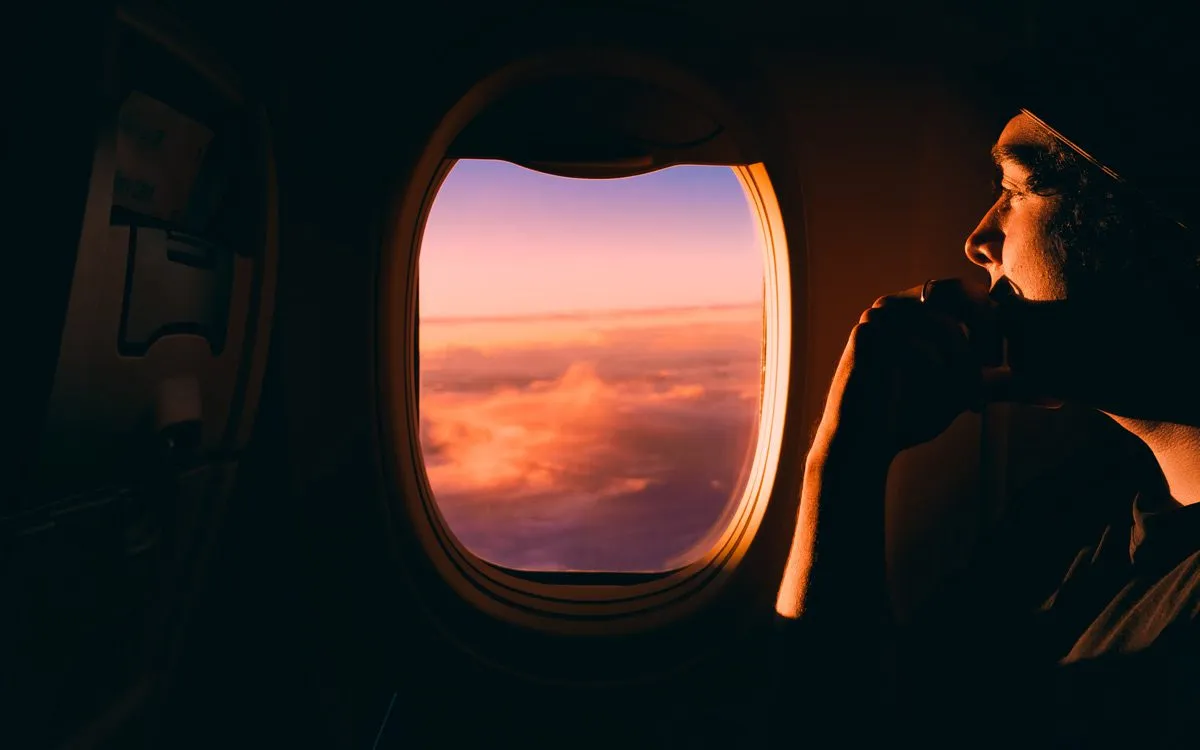 Man looks at the sunset through the airplane window