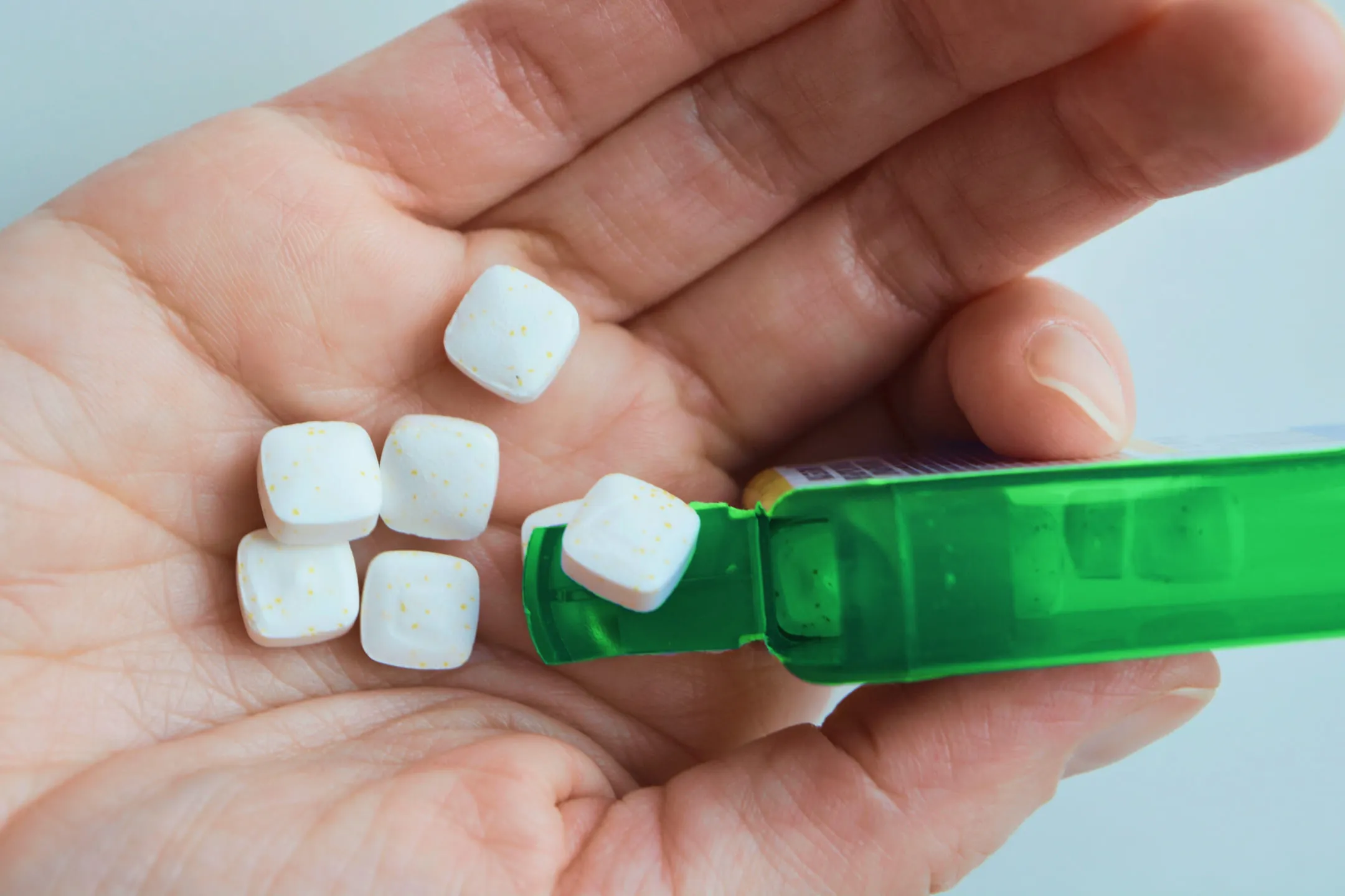 Person pouring mint lozenges into hand